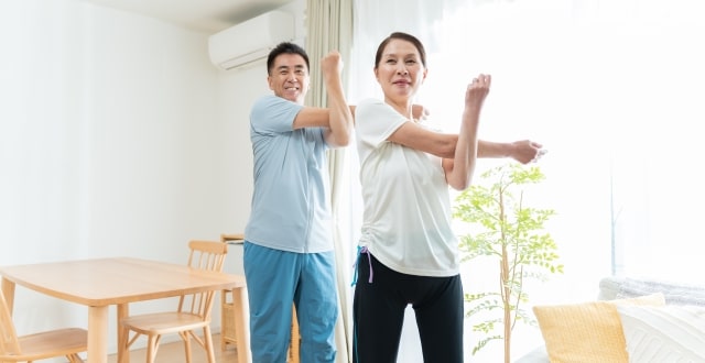 自宅で夫婦が一緒に無理のない体操をしている様子