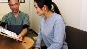 施術前に、整体師と利用者が資料を見ながら話をしている様子
