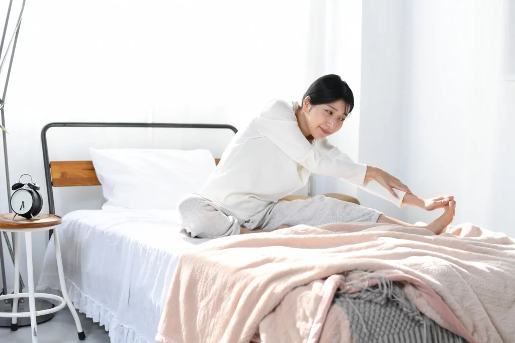 朝起きると腰が痛い人がベッドの上で体を伸ばすストレッチ