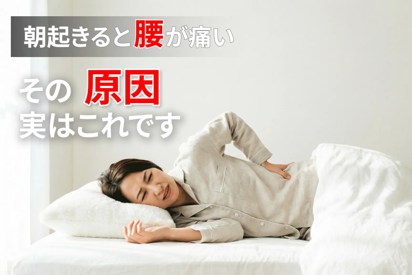 朝起きると腰が痛い女性　ベッドで腰に手を当てている様子